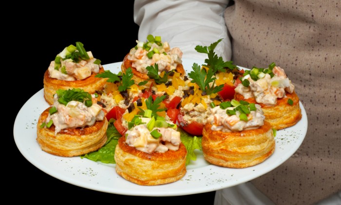 tarlet dengan salad di piring, dipegang oleh pelayan
