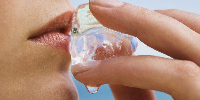 Mujer sosteniendo el cubo de hielo a sus labios