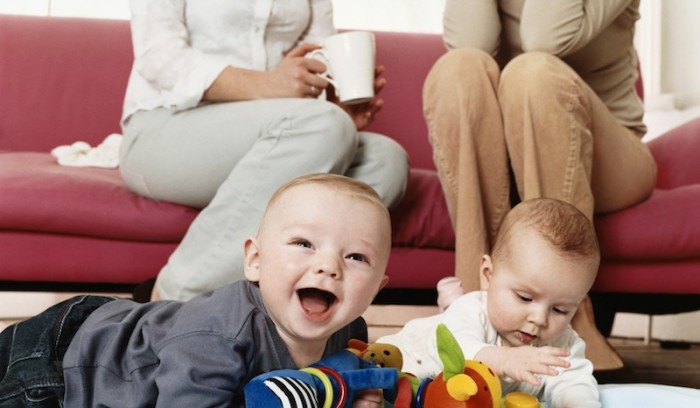 Two Babies Playing with Cuddly Toys on a Living Room Floor