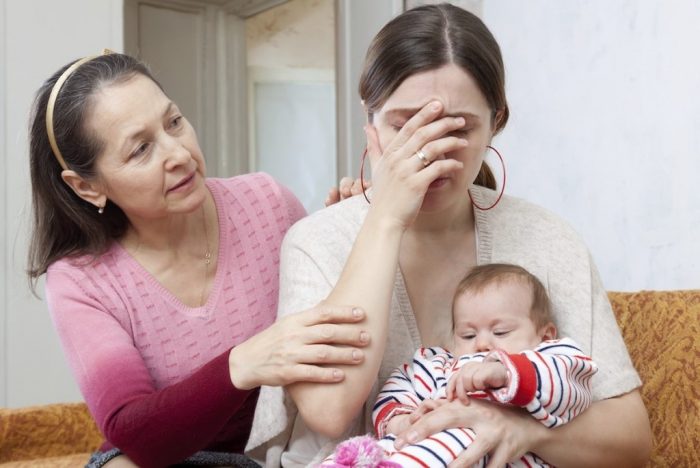 Mature woman comforts crying daughter with baby