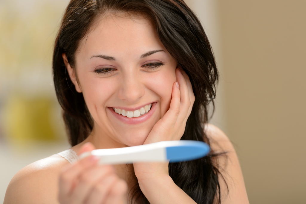 Delighted woman holding pregnancy test