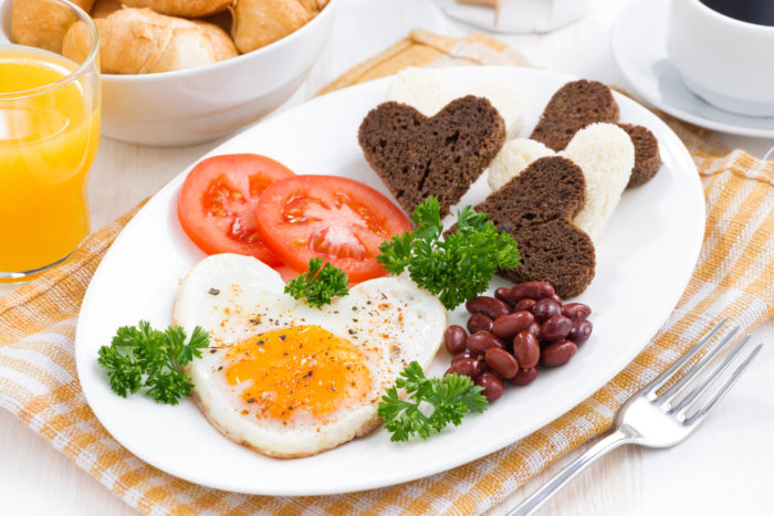 fried eggs in the form of heart for breakfast Valentine's Day on white plate, horizontal
