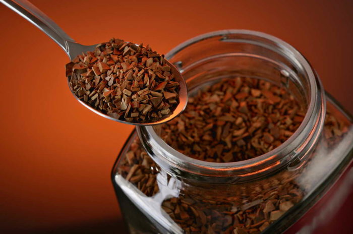 Spoon with instant coffee on a dark red background