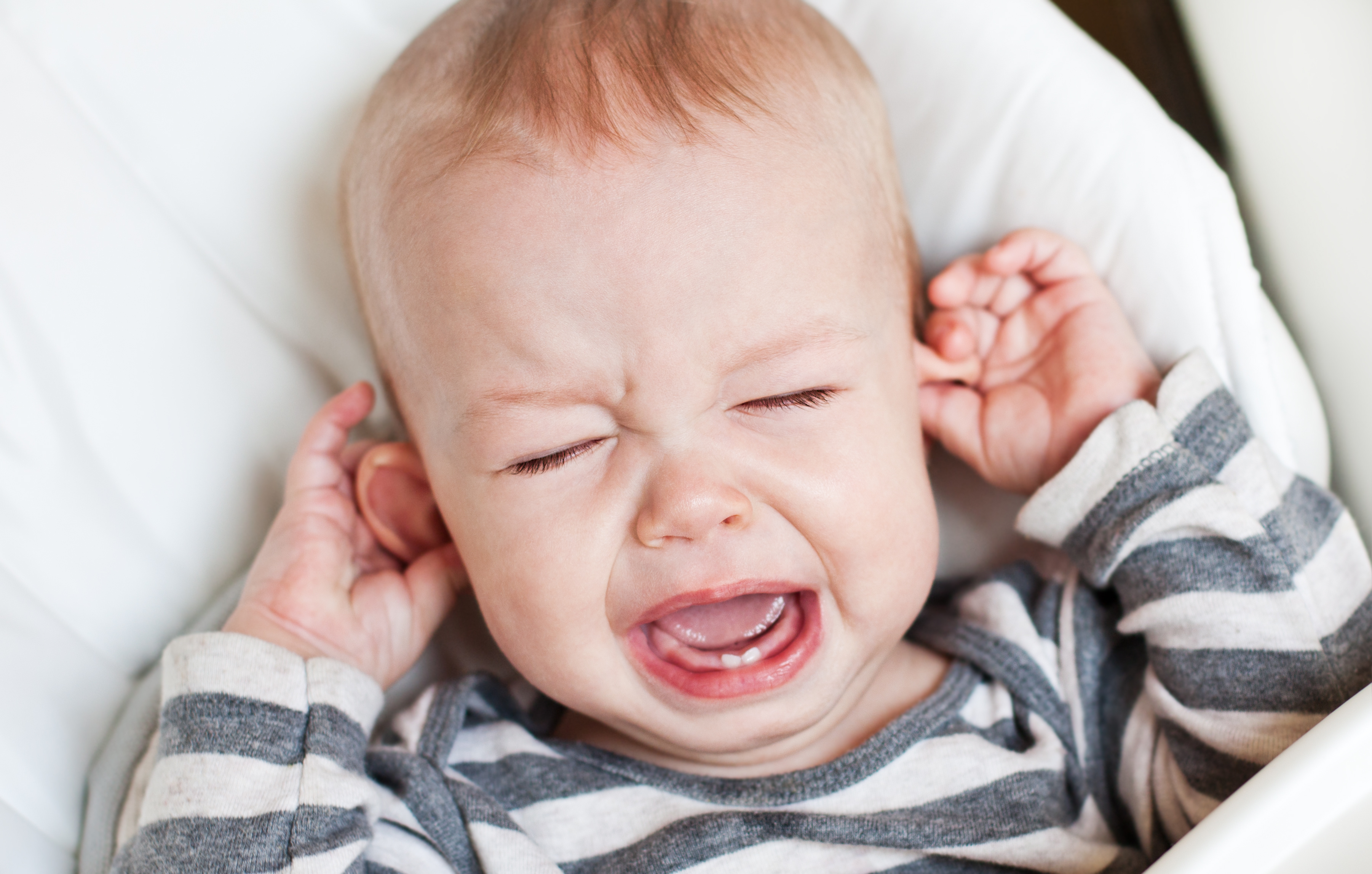 cute little boy crying holding his ear