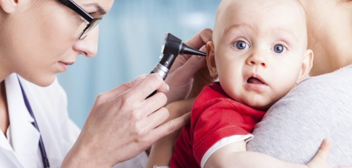 Doctor examining baby boy with otoscope