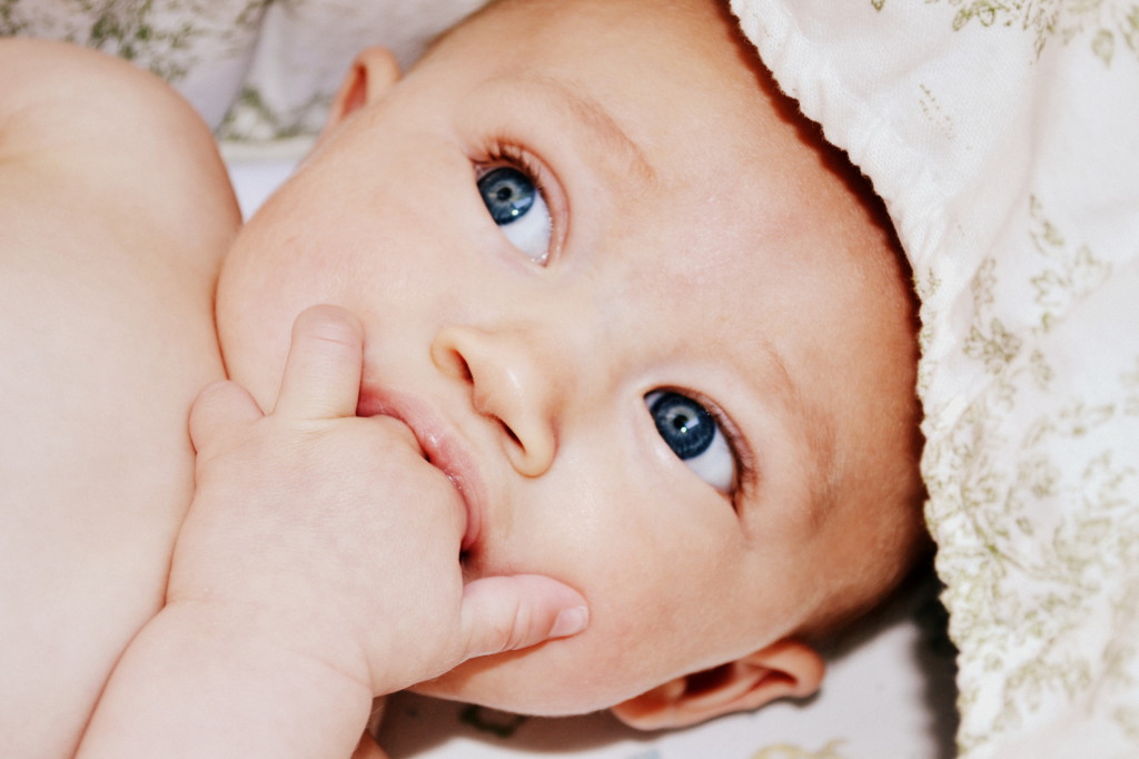 Blue eyed baby sucking on two fingers