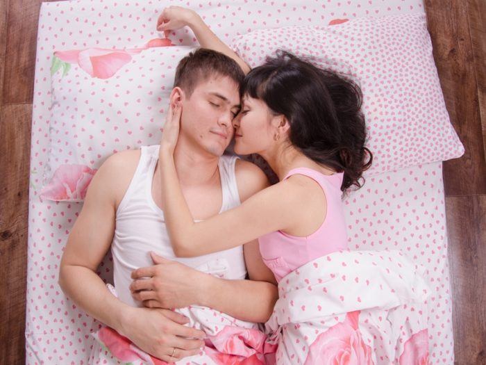 El marido abraza a su joven esposa en la cama